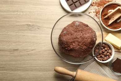 Photo of Chocolate dough and ingredients on wooden table, flat lay. Space for text