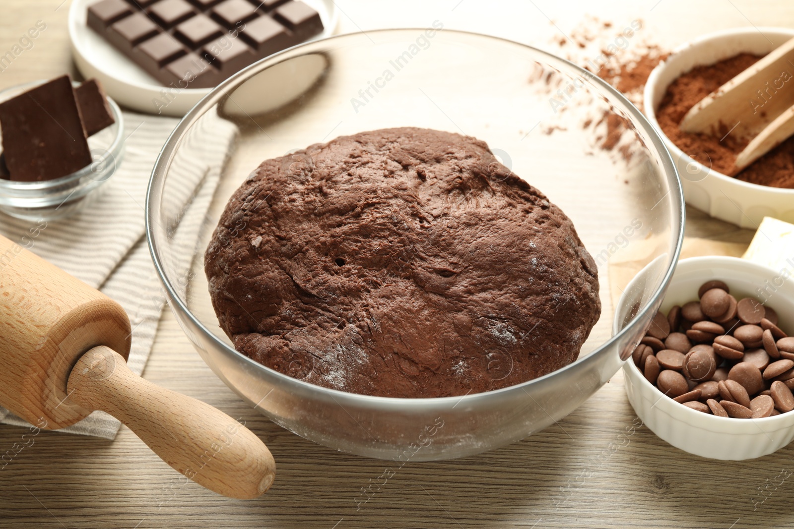 Photo of Chocolate dough and ingredients on wooden table, closeup