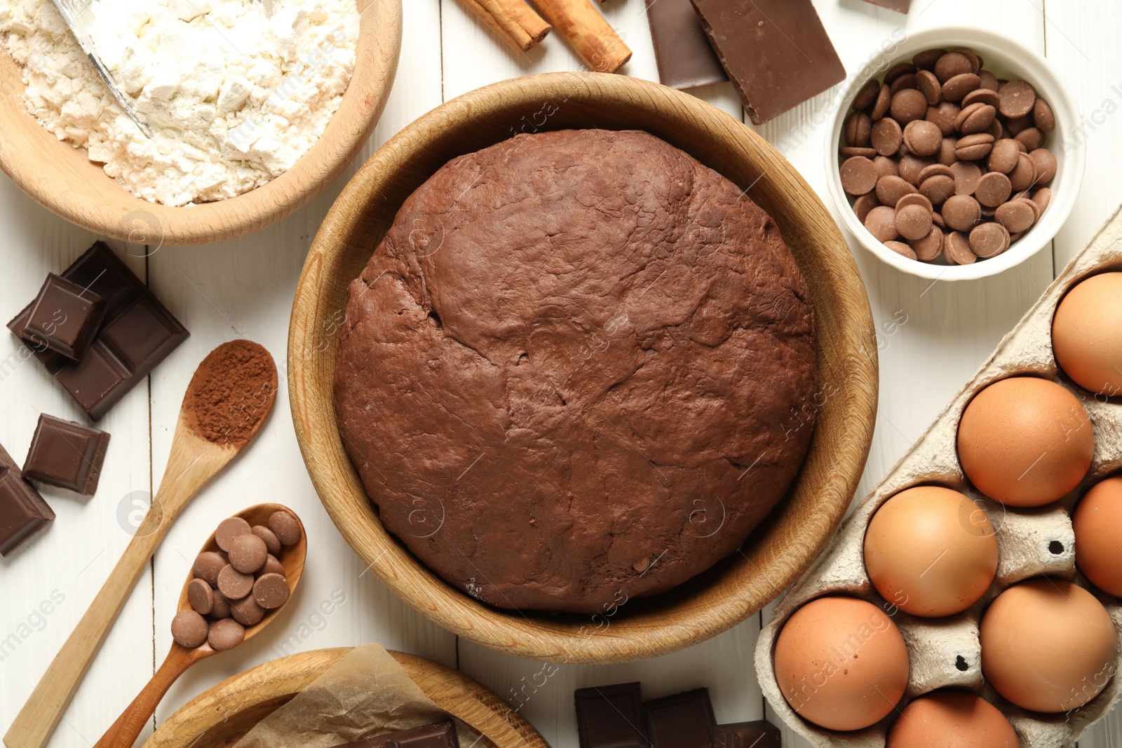 Photo of Chocolate dough and ingredients on white wooden table, flat lay