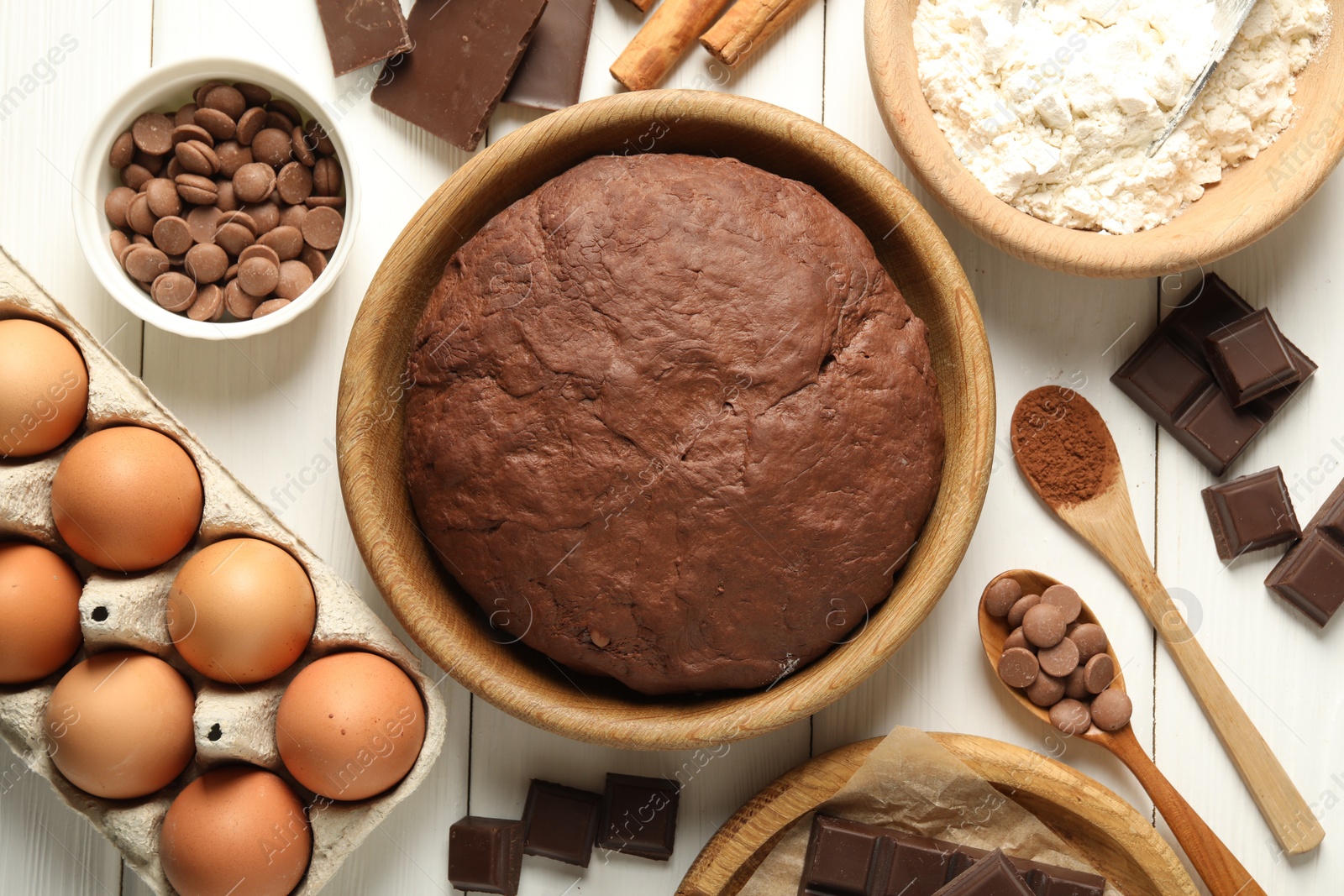 Photo of Chocolate dough and ingredients on white wooden table, flat lay