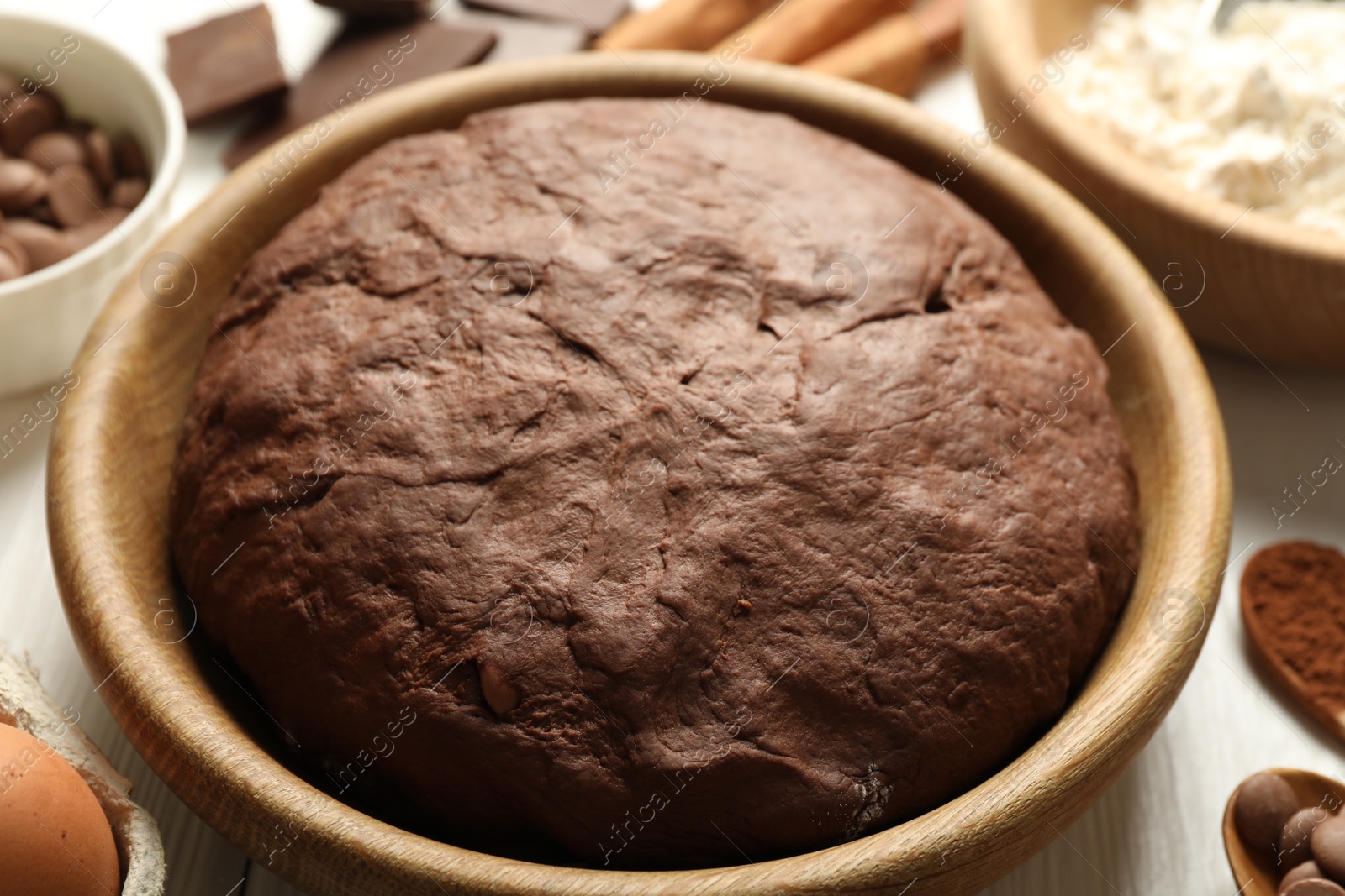 Photo of Chocolate dough and ingredients on white wooden table, closeup