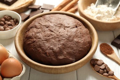 Photo of Chocolate dough and ingredients on white wooden table, closeup