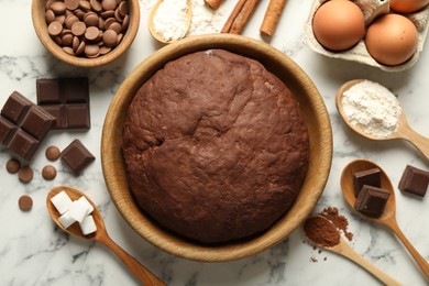 Photo of Chocolate dough and ingredients on white marble table, flat lay