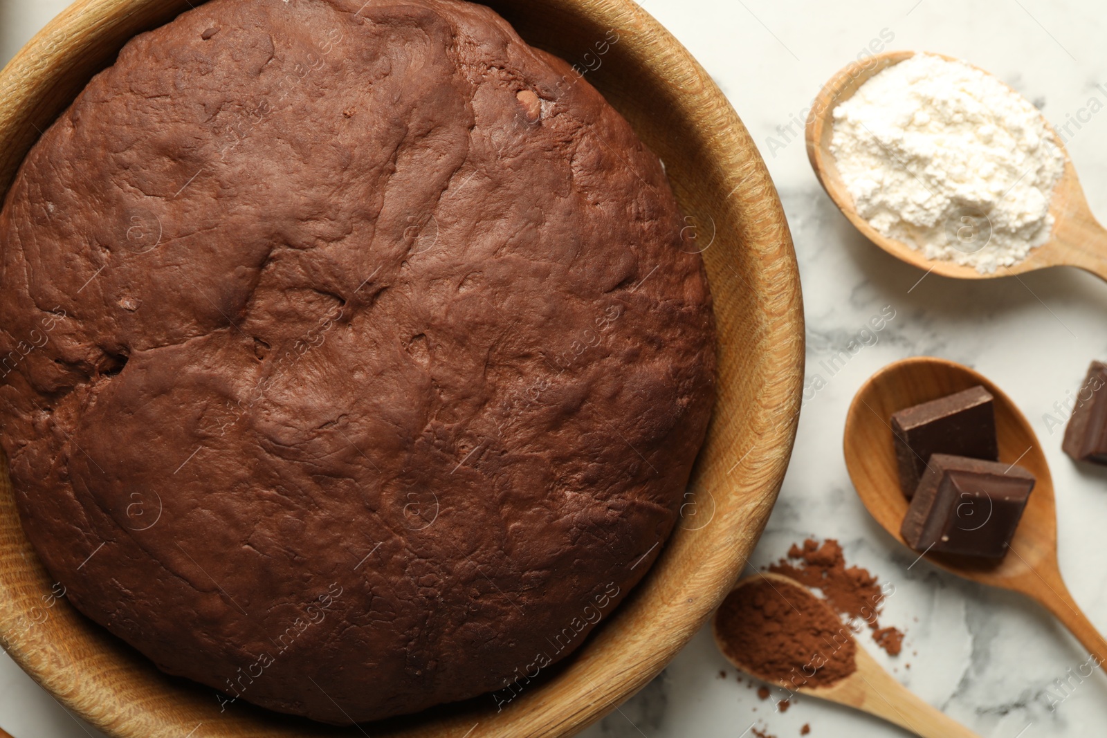 Photo of Chocolate dough and ingredients on white marble table, flat lay