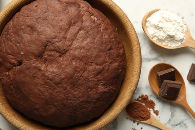 Photo of Chocolate dough and ingredients on white marble table, flat lay