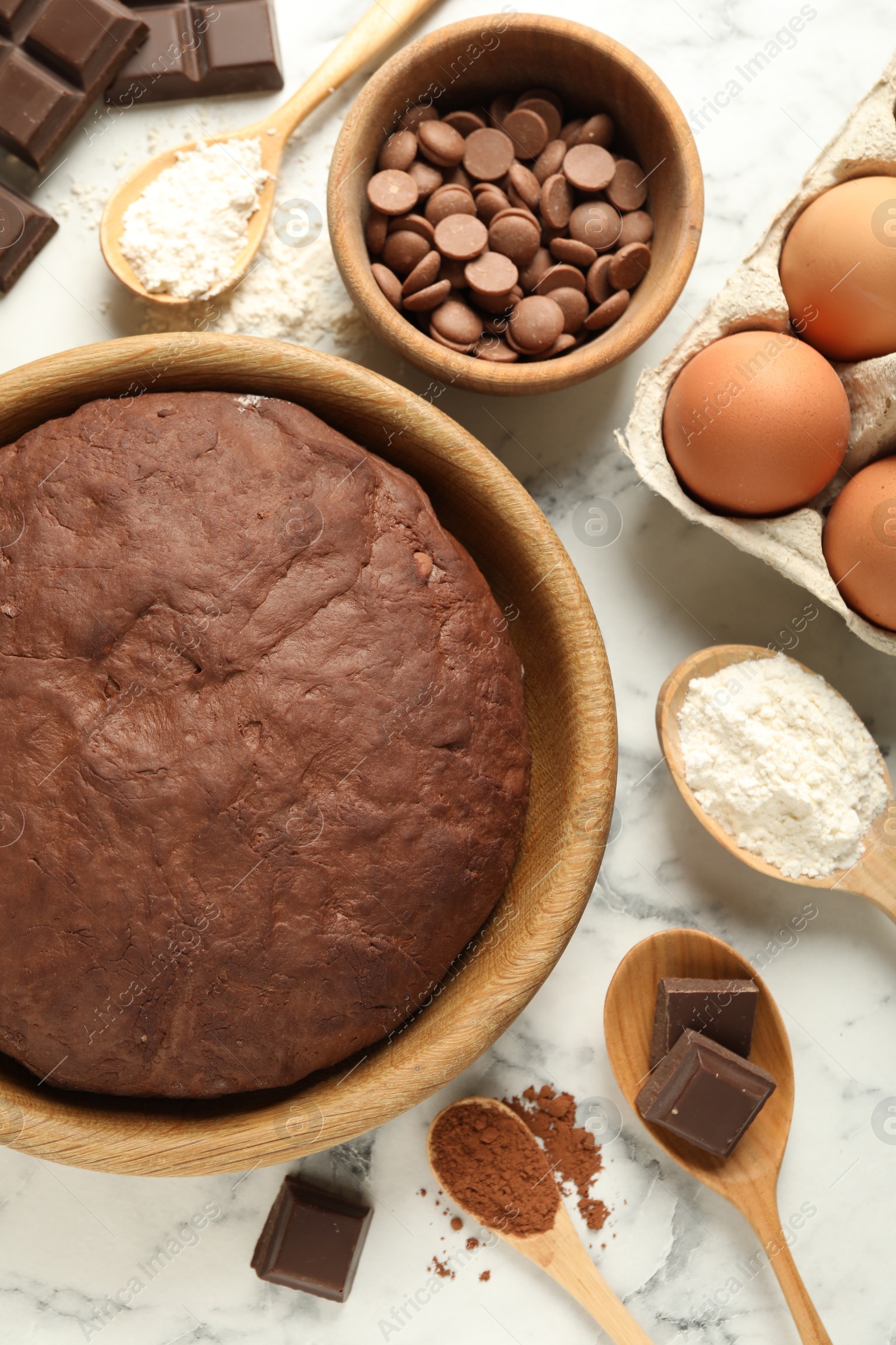 Photo of Chocolate dough and ingredients on white marble table, flat lay