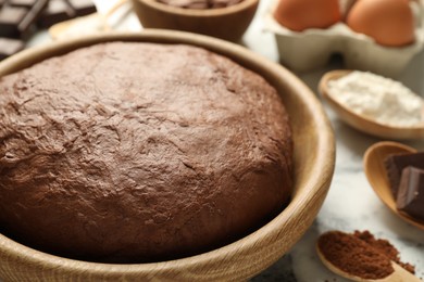 Photo of Chocolate dough and ingredients on white marble table, closeup