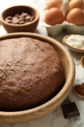 Photo of Chocolate dough and ingredients on white marble table, closeup