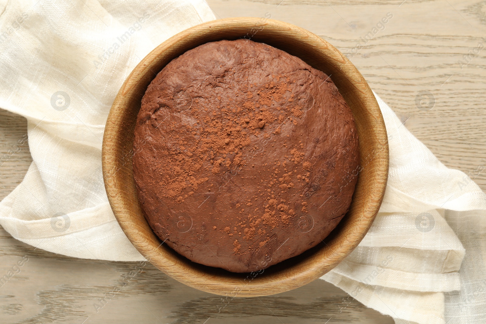 Photo of Chocolate dough in bowl on wooden table, top view