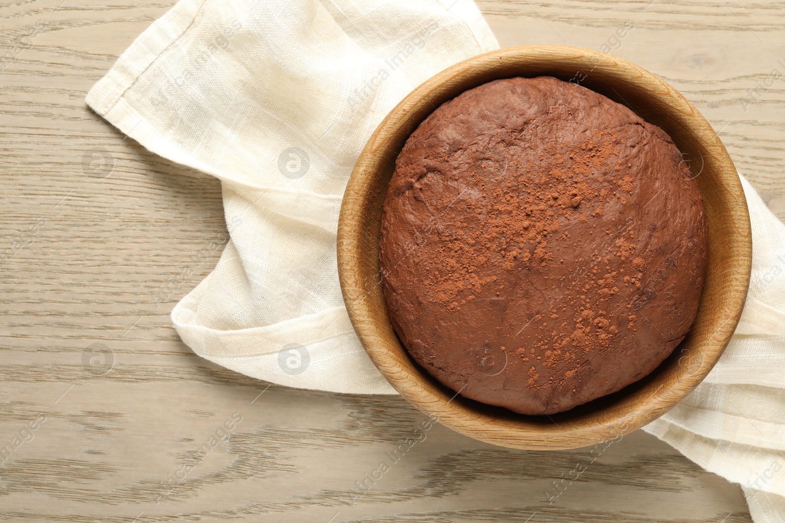 Photo of Chocolate dough in bowl on wooden table, top view