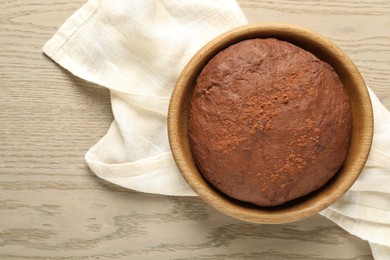 Photo of Chocolate dough in bowl on wooden table, top view