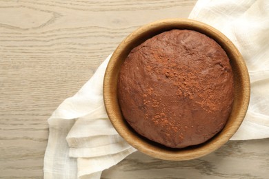 Photo of Chocolate dough in bowl on wooden table, top view