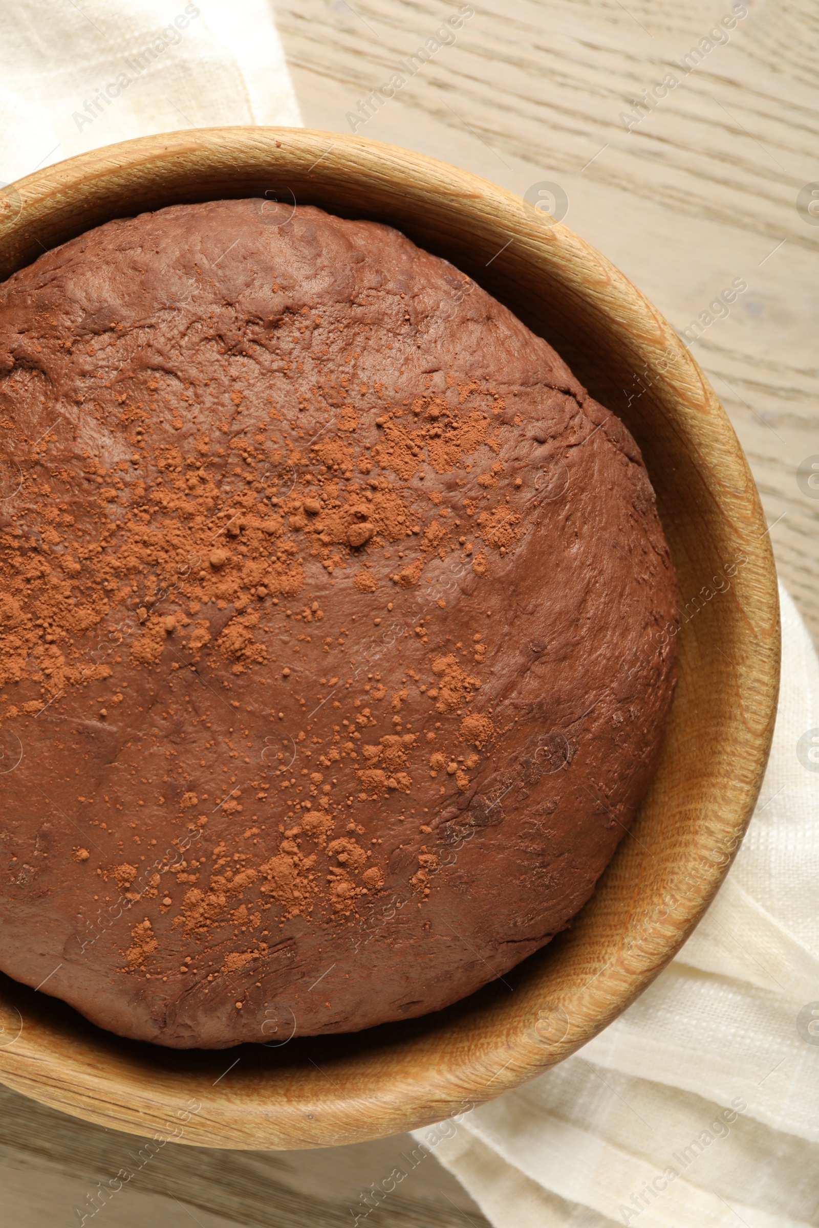 Photo of Chocolate dough in bowl on wooden table, top view