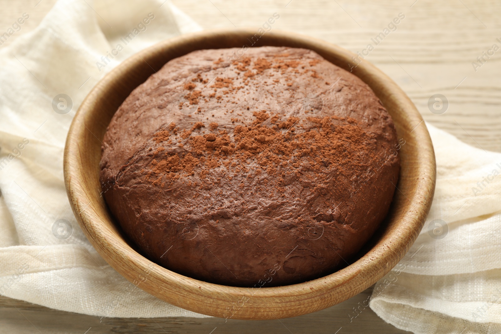 Photo of Chocolate dough in bowl on wooden table, closeup