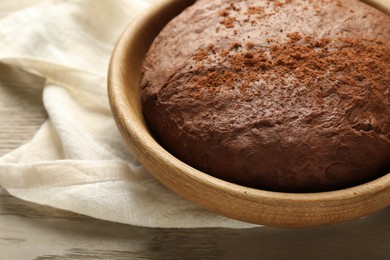 Photo of Chocolate dough in bowl on wooden table, closeup