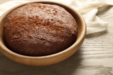 Photo of Chocolate dough in bowl on wooden table, closeup