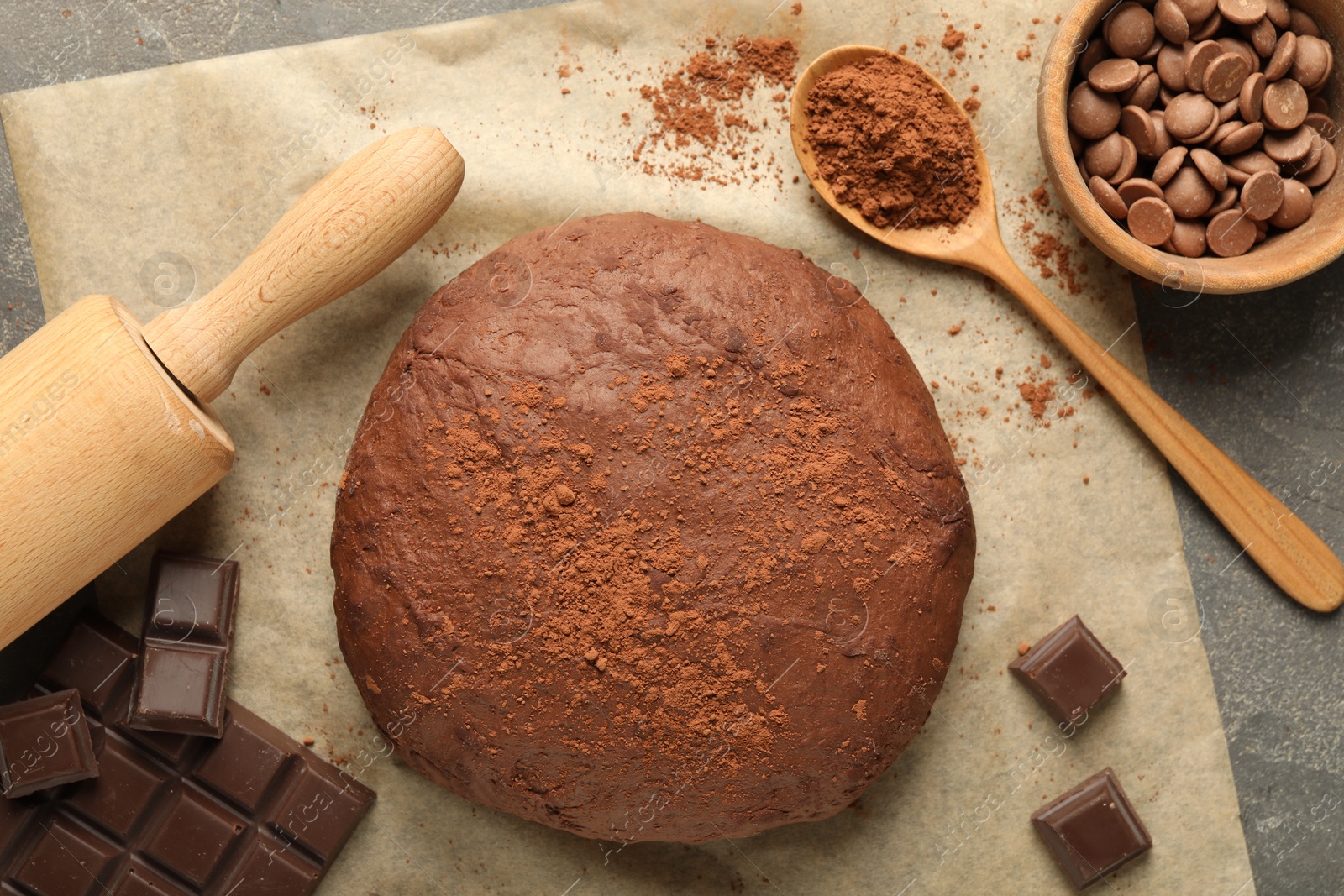 Photo of Chocolate dough and ingredients on grey table, flat lay