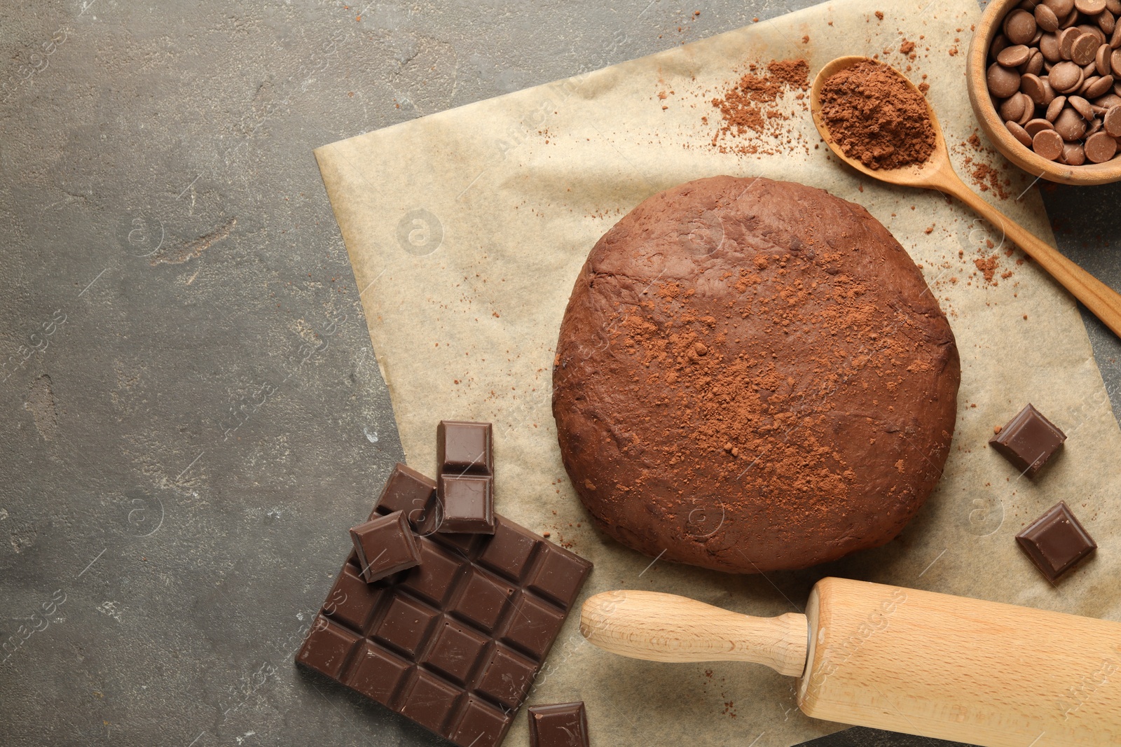 Photo of Chocolate dough and ingredients on grey table, flat lay. Space for text