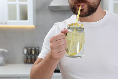 Photo of Man drinking water with lemon in kitchen, closeup. Space for text