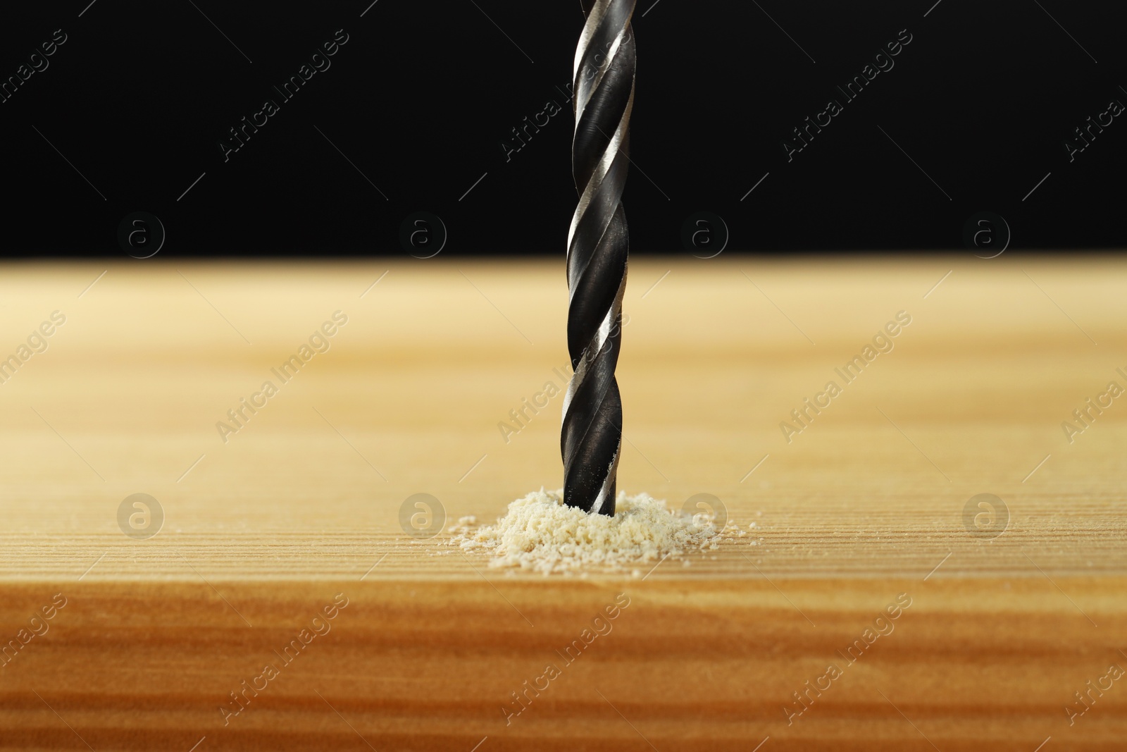 Photo of Drilling hole in wooden plank on black background, closeup