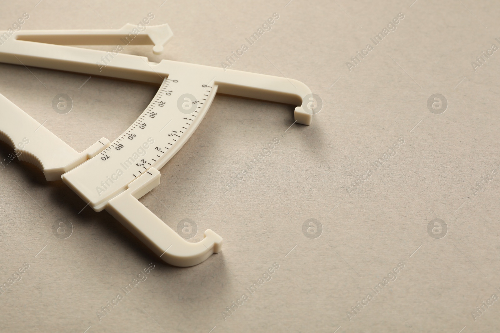 Photo of Plastic body fat caliper on grey background, closeup. Space for text