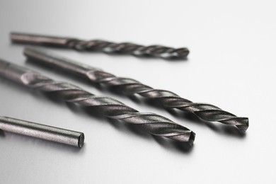 Photo of Many different drill bits on light grey background, closeup