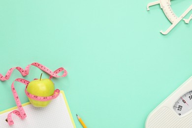 Flat lay composition with body fat caliper and measuring tape on turquoise background. Space for text