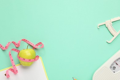 Flat lay composition with body fat caliper and measuring tape on turquoise background. Space for text