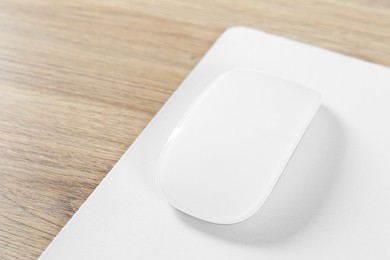 Photo of White computer mouse and mousepad on wooden table