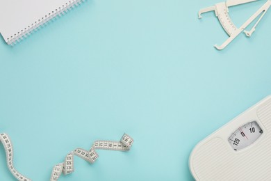 Photo of Body fat caliper, measuring tape, scale and notebook on light blue background, flat lay. Space for text