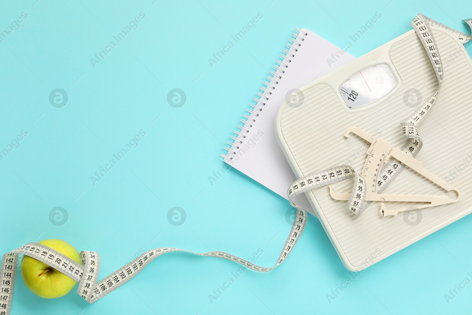 Photo of Body fat caliper, measuring tape, apple and notebook on light blue background, flat lay. Space for text