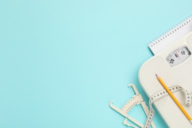 Photo of Body fat caliper, measuring tape, scale, pencil and notebook on light blue background, flat lay. Space for text