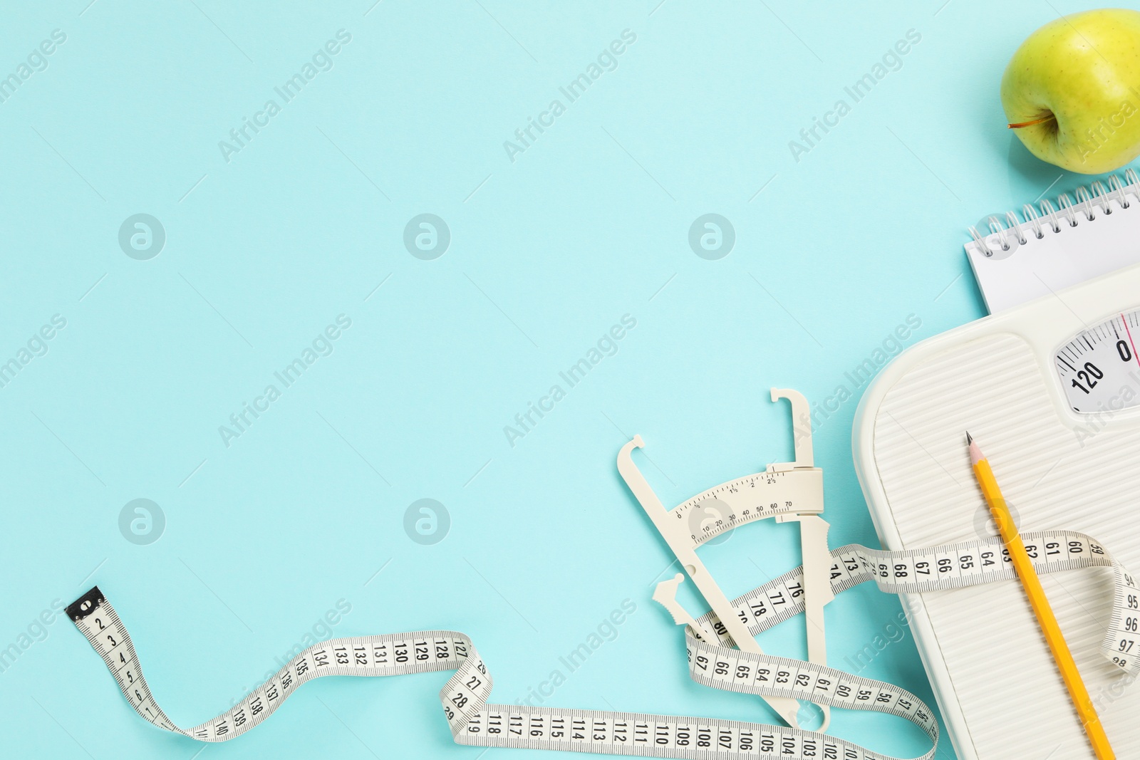 Photo of Body fat caliper, measuring tape, apple and notebook on light blue background, flat lay. Space for text