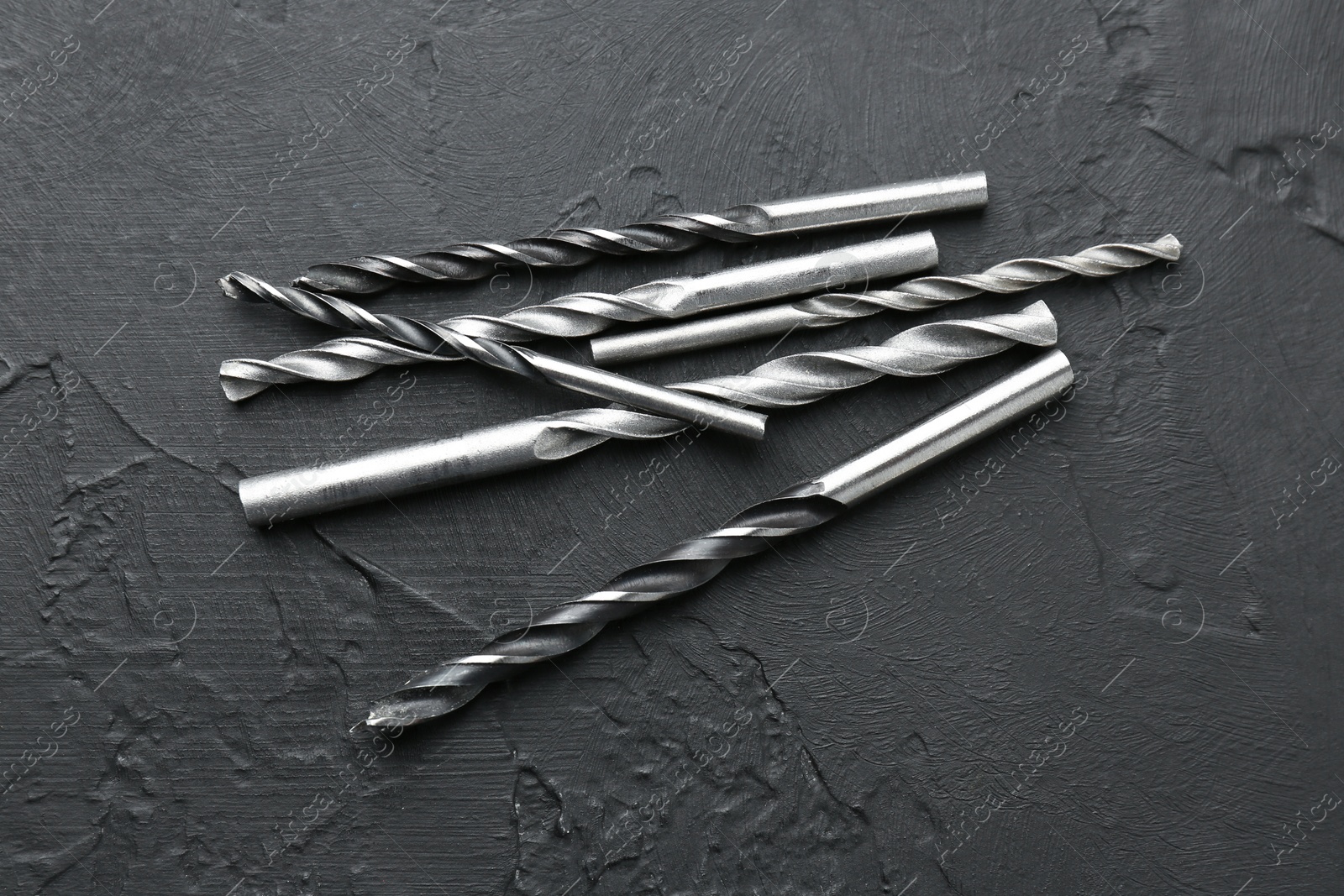 Photo of Many different drill bits on black table, top view