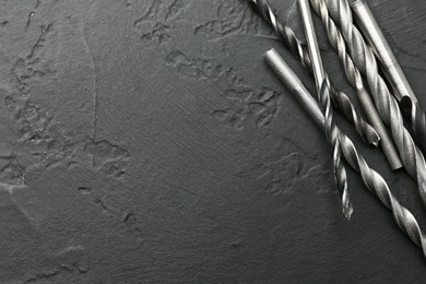 Photo of Many different drill bits on black table, top view. Space for text