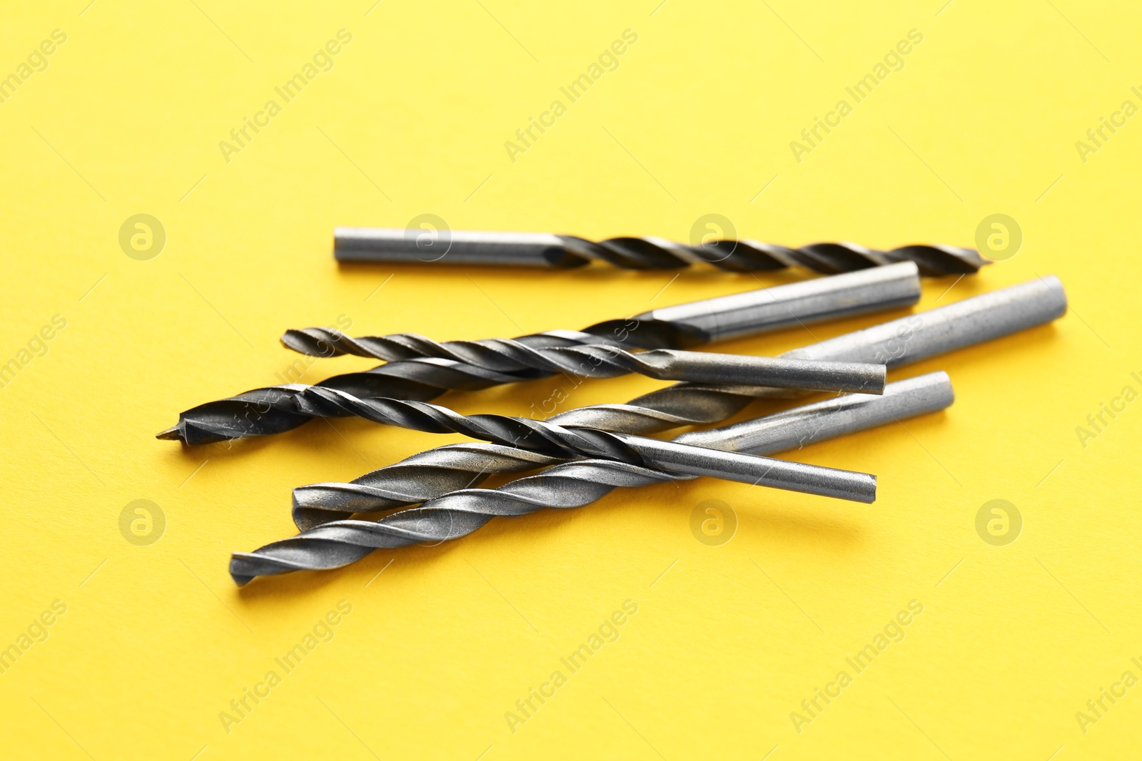 Photo of Many different drill bits on yellow background