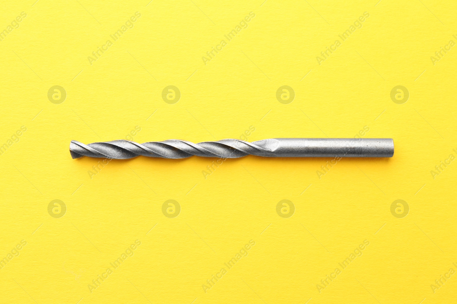 Photo of One drill bit on yellow background, top view