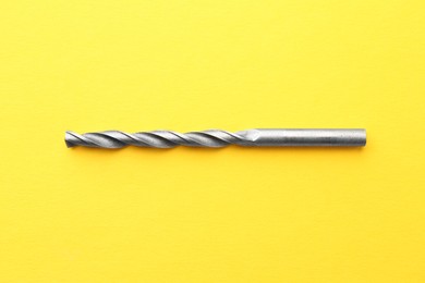 Photo of One drill bit on yellow background, top view