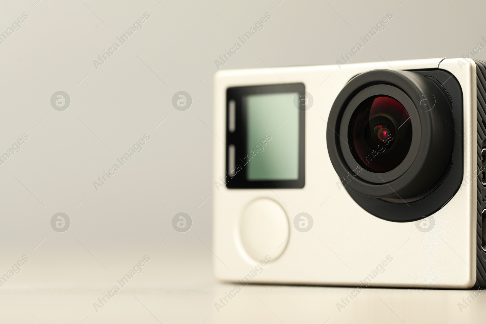 Photo of Modern action camera on light background, closeup. Space for text