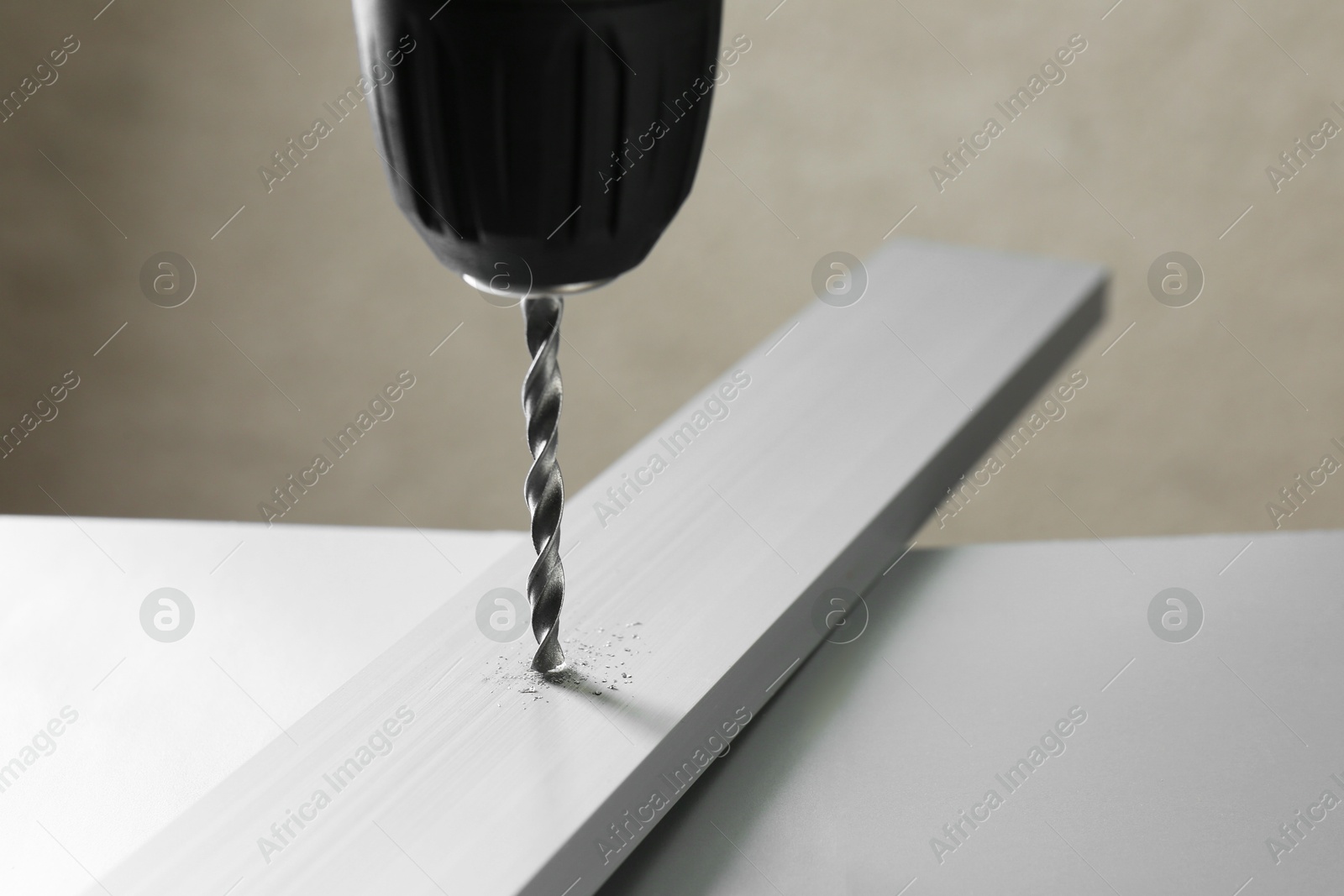 Photo of Drilling hole in plank on table against gray background, closeup