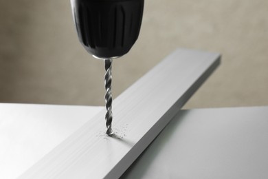 Photo of Drilling hole in plank on table against gray background, closeup