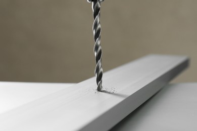 Photo of Drilling hole in plank on table against gray background, closeup