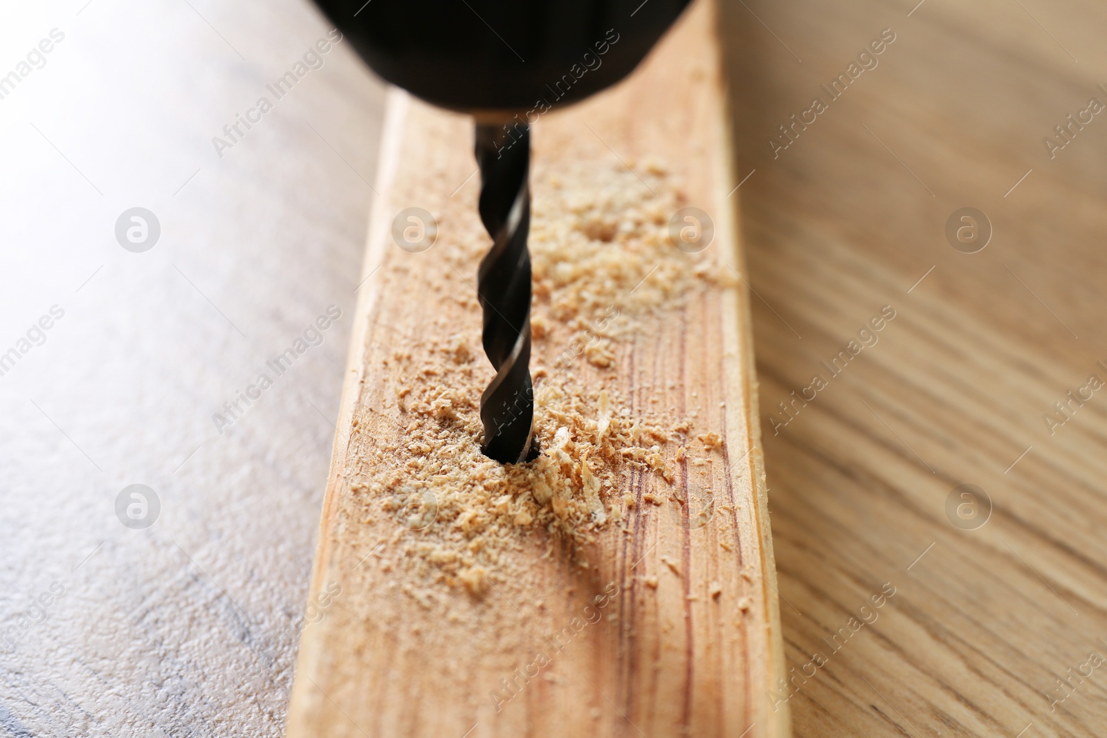 Photo of Drilling hole in plank on wooden table, closeup