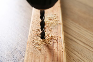 Drilling hole in plank on wooden table, closeup