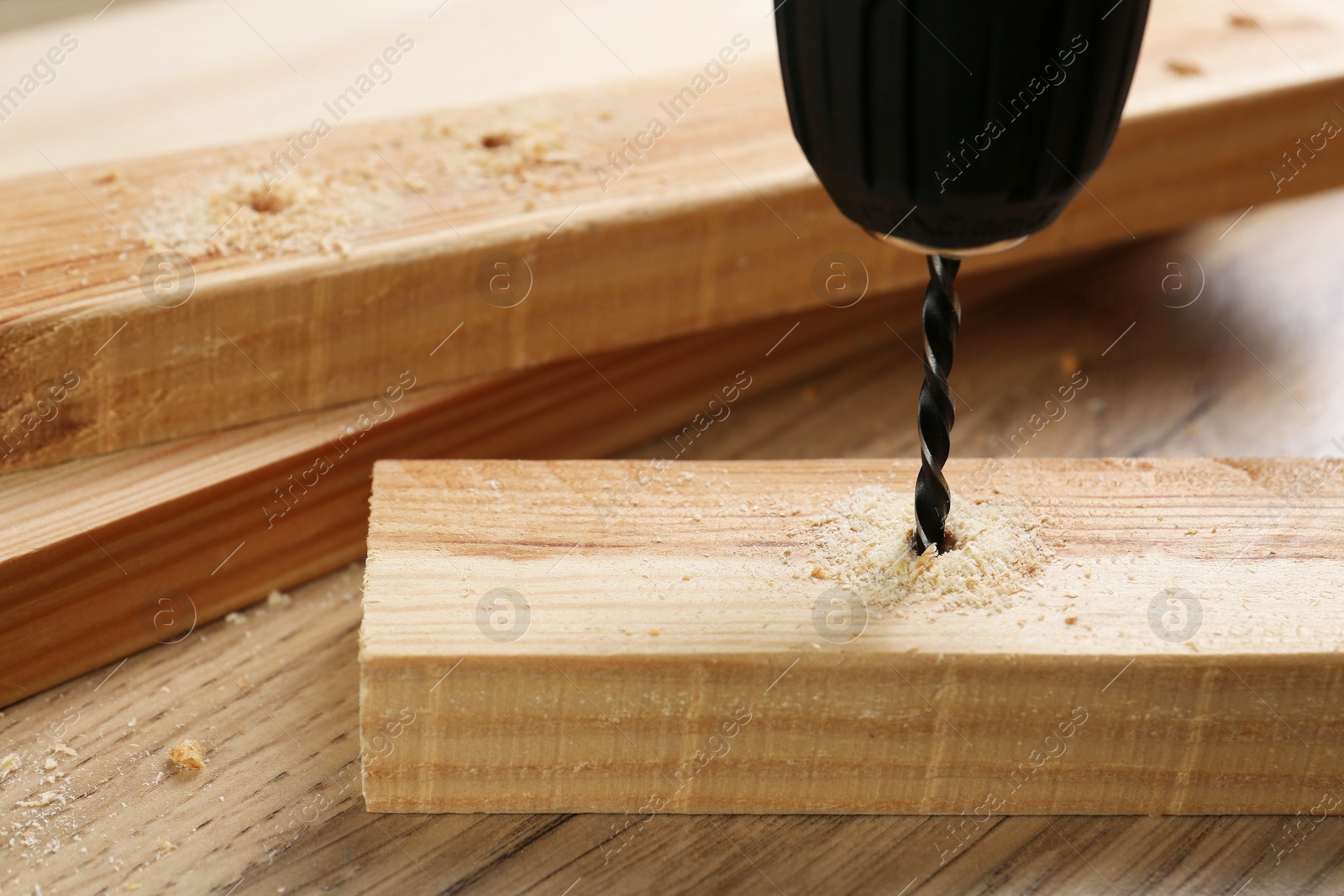 Photo of Drilling hole in plank on wooden table, closeup