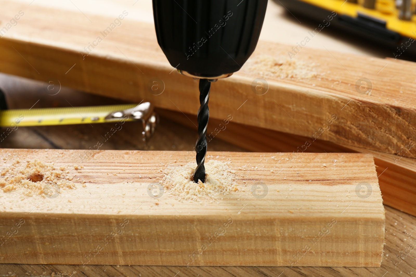 Photo of Drilling hole in plank on wooden table, closeup