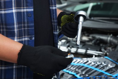 Photo of Auto mechanic with torque wrench at automobile repair shop, closeup