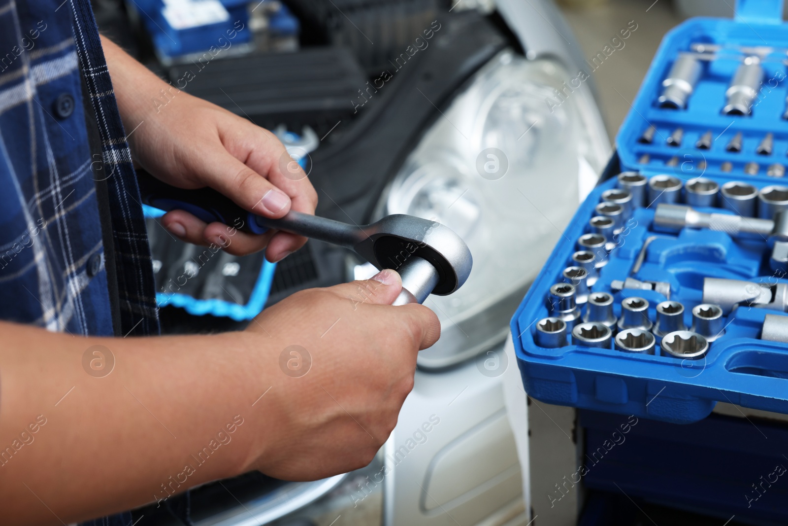 Photo of Auto mechanic with torque wrench at automobile repair shop, closeup