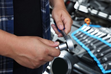 Auto mechanic with torque wrench at automobile repair shop, closeup