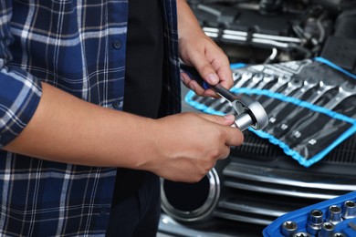 Photo of Auto mechanic with torque wrench at automobile repair shop, closeup